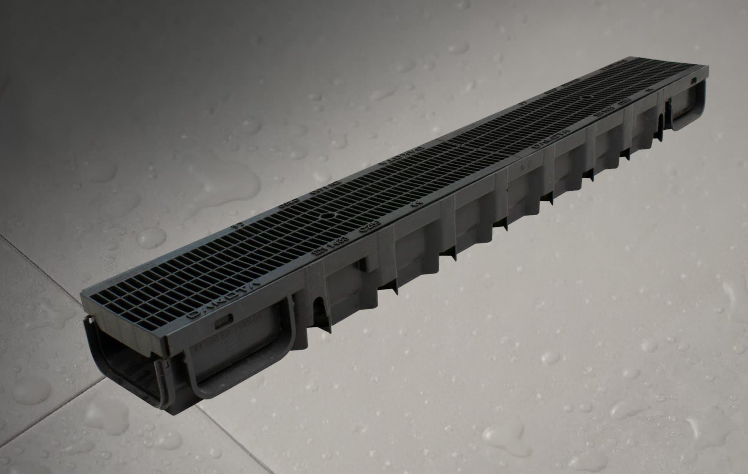 Drainage channel with black grating on a wet tiled floor